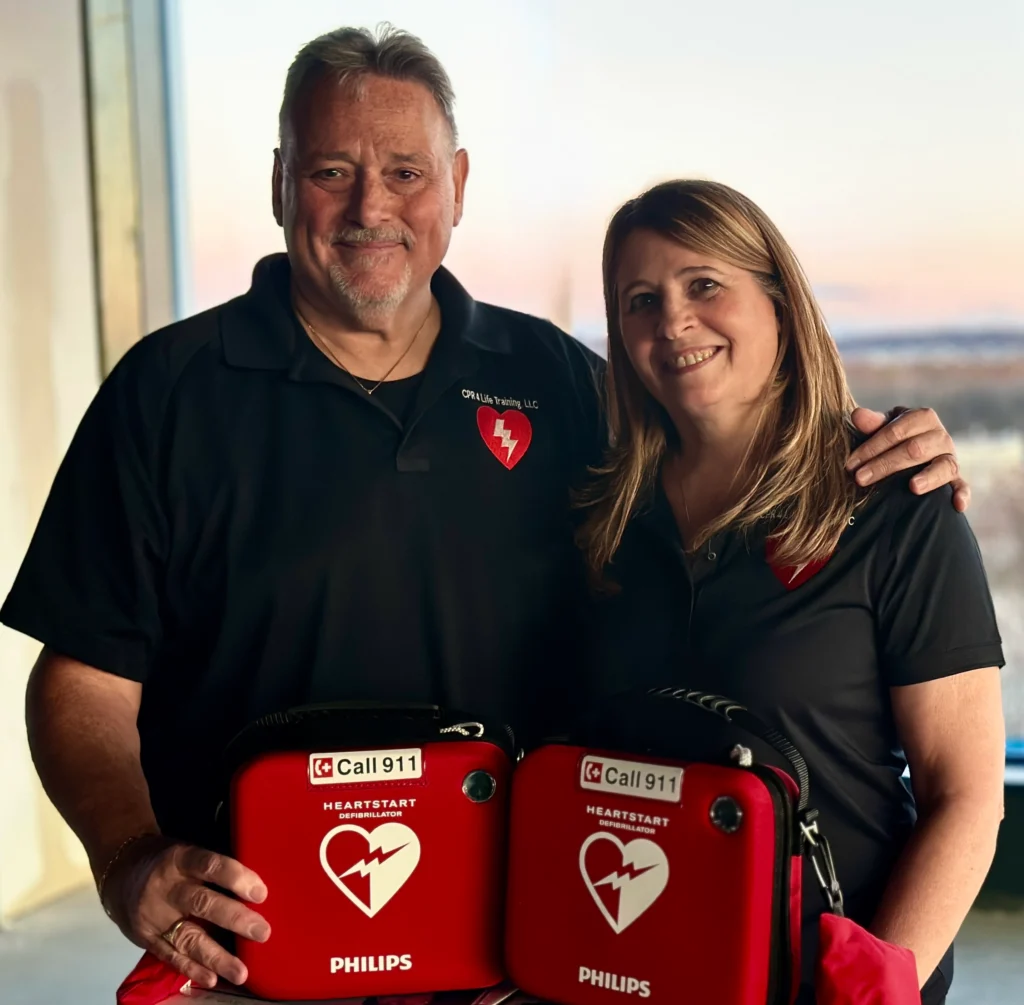 Two CPR instructors holding AED training kits during a life-saving skills training session